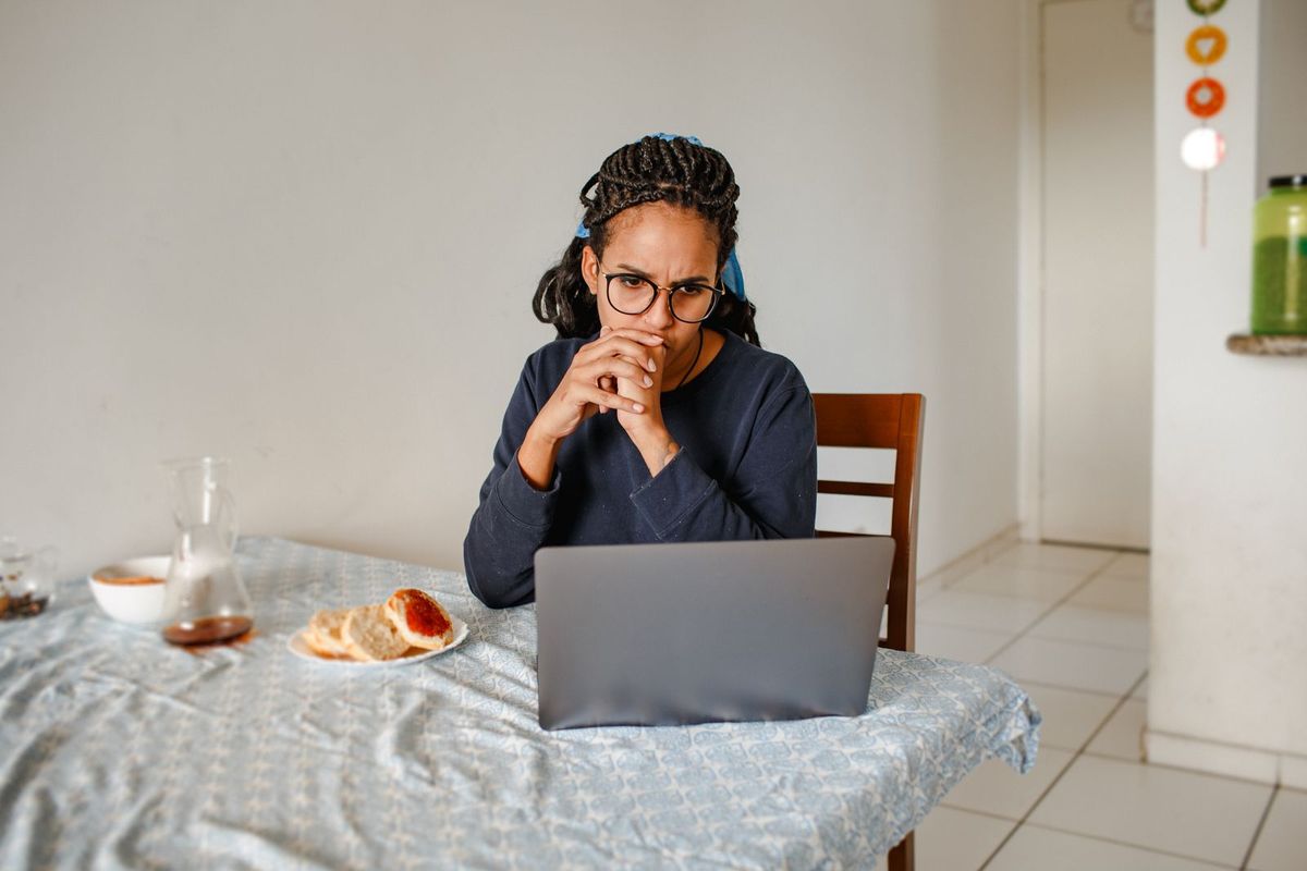 Frau um die 40 konzentriert am Laptop, daneben das Frühstück