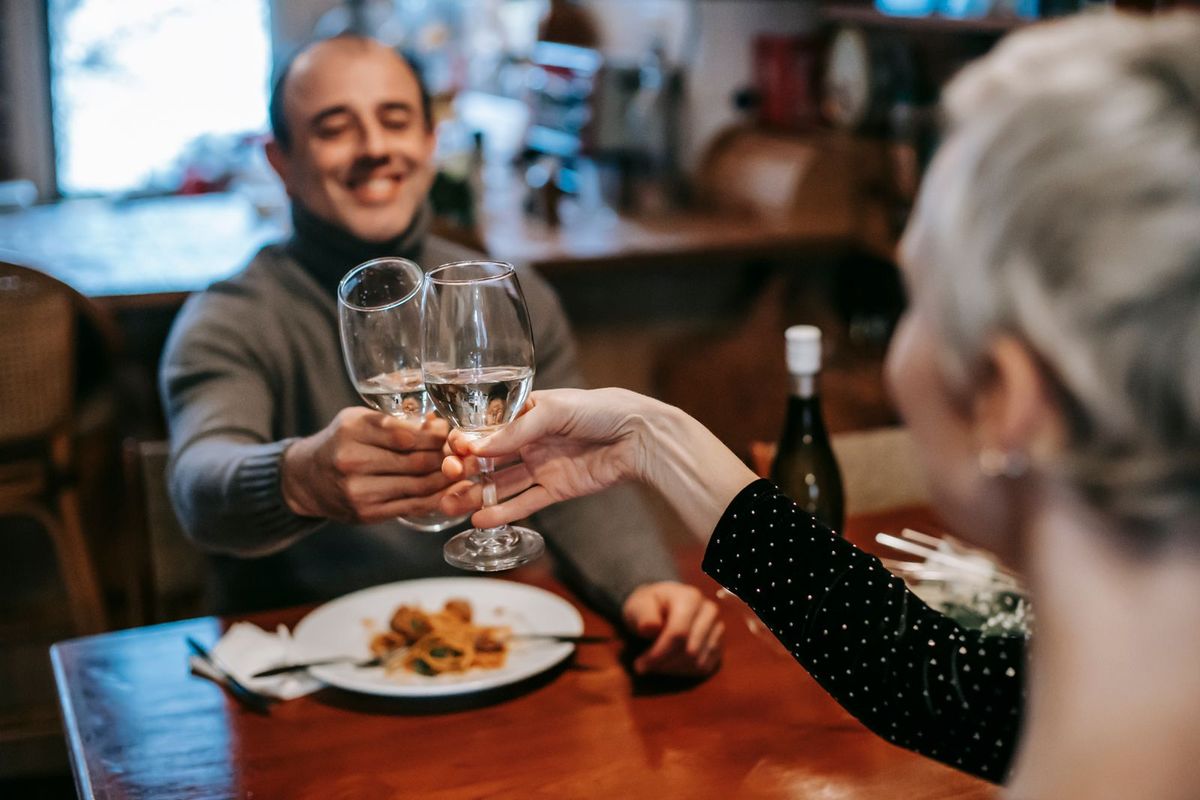 Paar stösst beim Abendessen mit Weisswein an