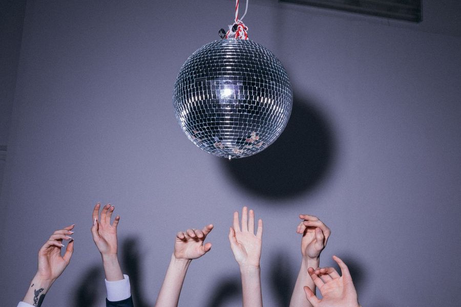 Hände in der Luft unter einer Discokugel