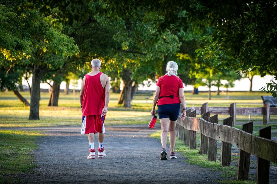 Zwei ältere Menschen spazieren durch einen Park